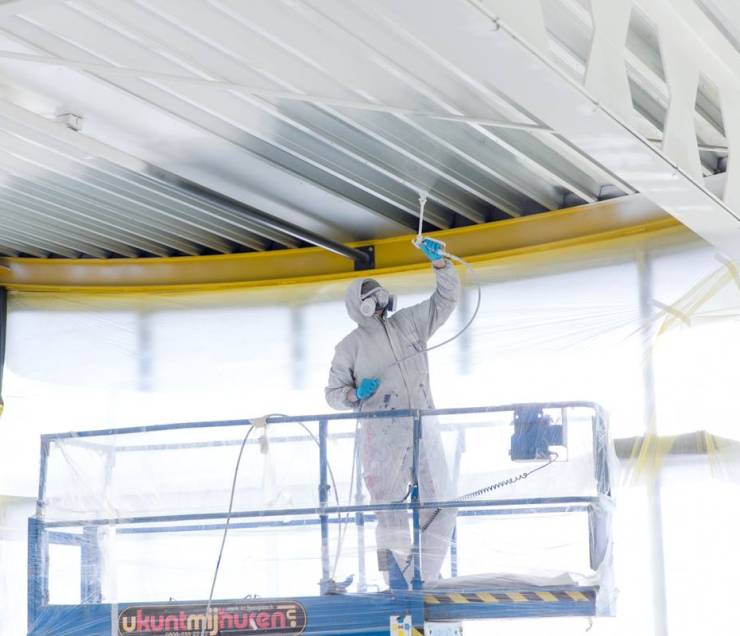 Coaten met hoogwerker Verfcoating bij een damwandplafond bij Broekhuis autogarage met hoogwerker
